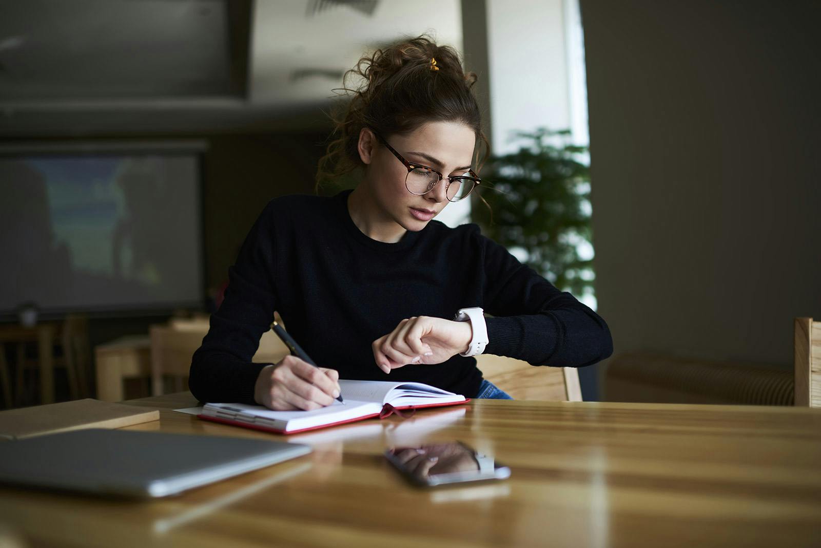 ejecutiva joven en sala de juntas revisa la hora en su reloj